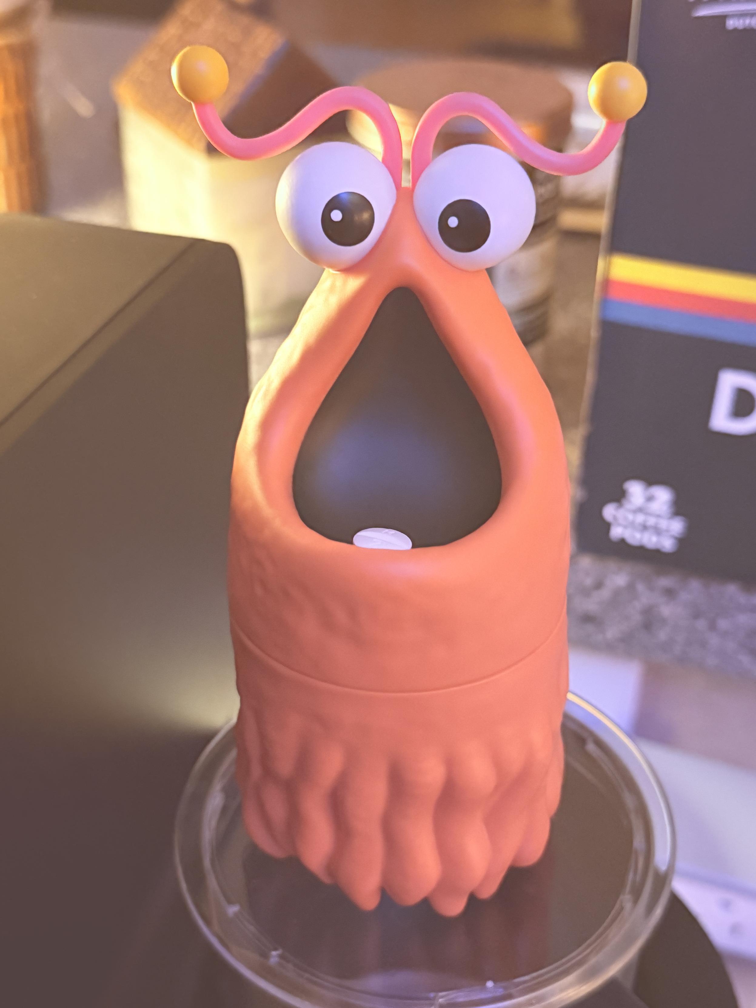 A plastic figurine of the a,Ken from Sesame Street. In the mouth, a single white pill sits ready to take with his morning coffee.
