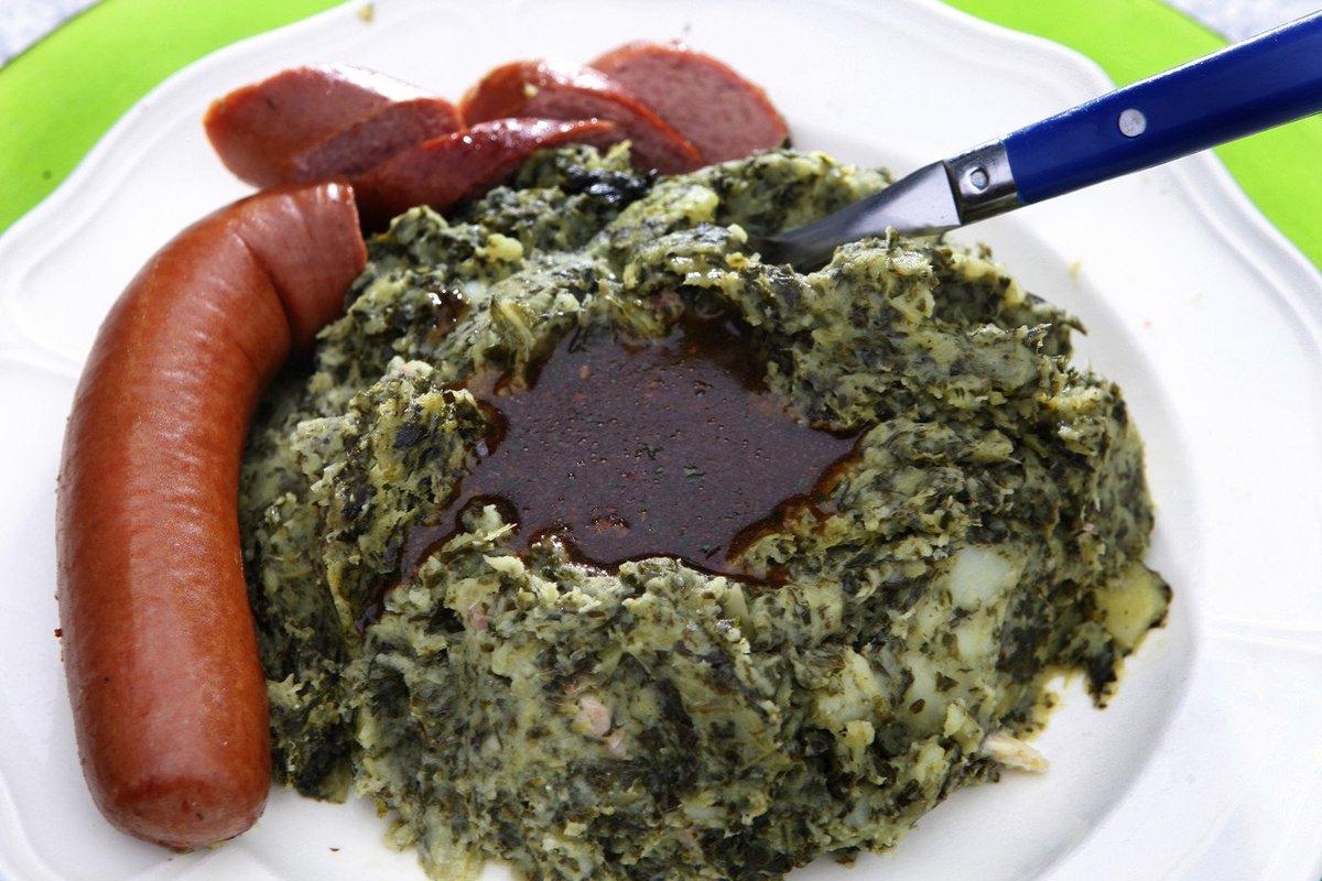 A volcano of "stamppot" made of mashed-potato and kale lies steaming on a plate. The mouth of the volcano is filled with gravy. Half a smoked sausage lies guarding the volcano, like a phallic dragon.