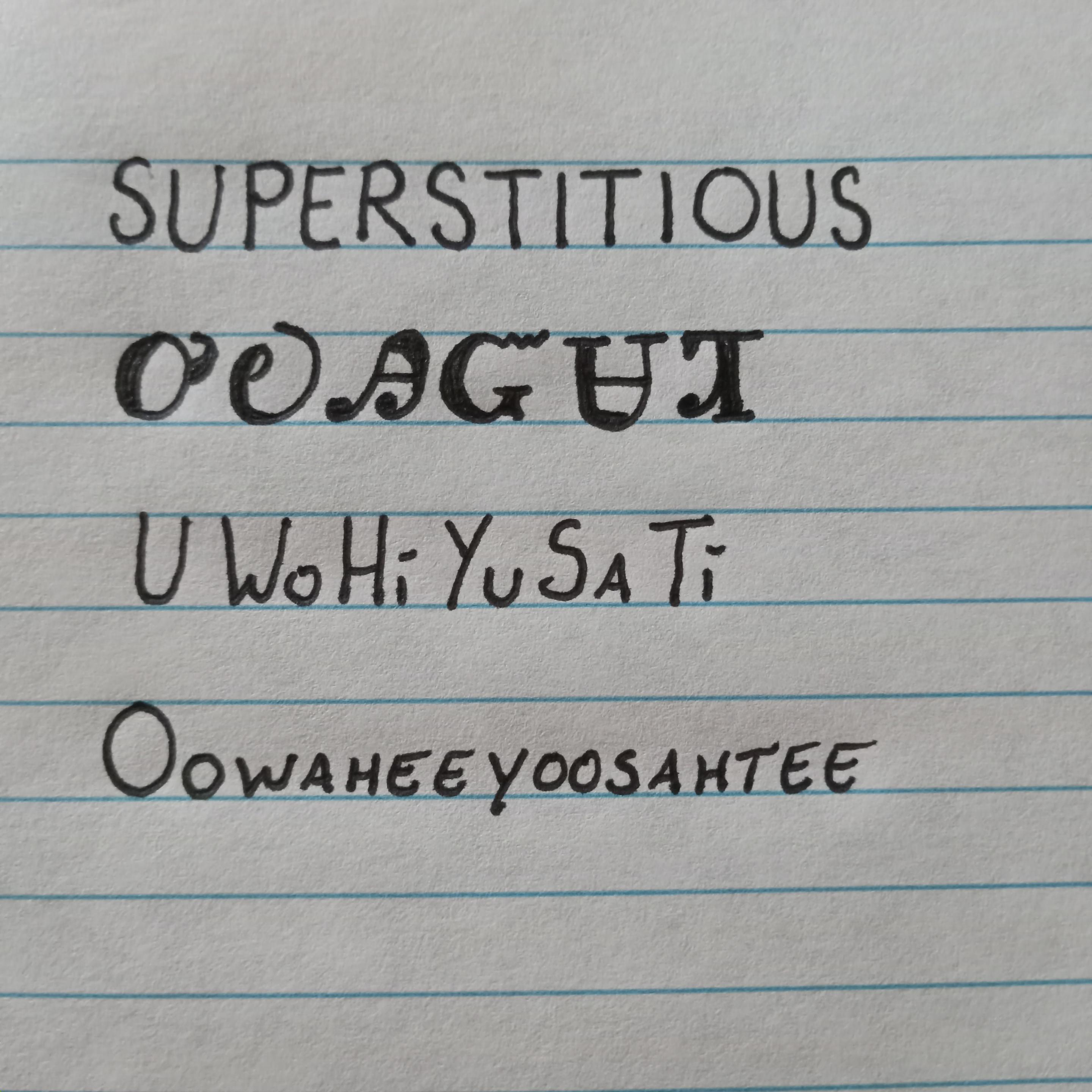 Image is line paper with writing showing an English word followed by how it is written in the Cherokee language followed by how it is spelled and pronounced. The word is superstitious and pronounced ooh-wah-heeyoosahtee