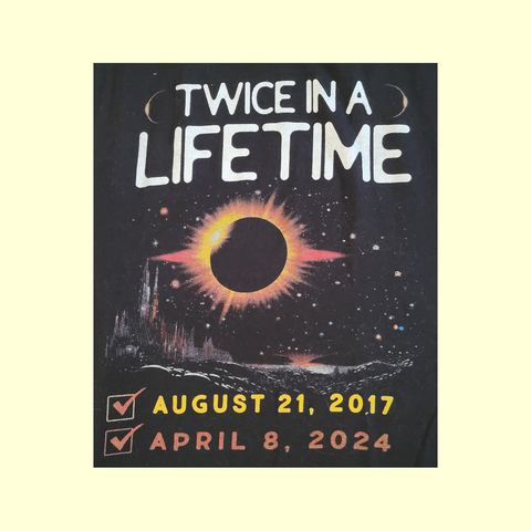 A T-shirt design shows a solar eclipse against a black, starry sky with the words "Twice in a Lifetime: August 21, 2017 and April 8, 2024"