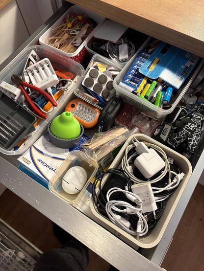 A junk drawer full of random stuff like tools, batteries and phone chargers.