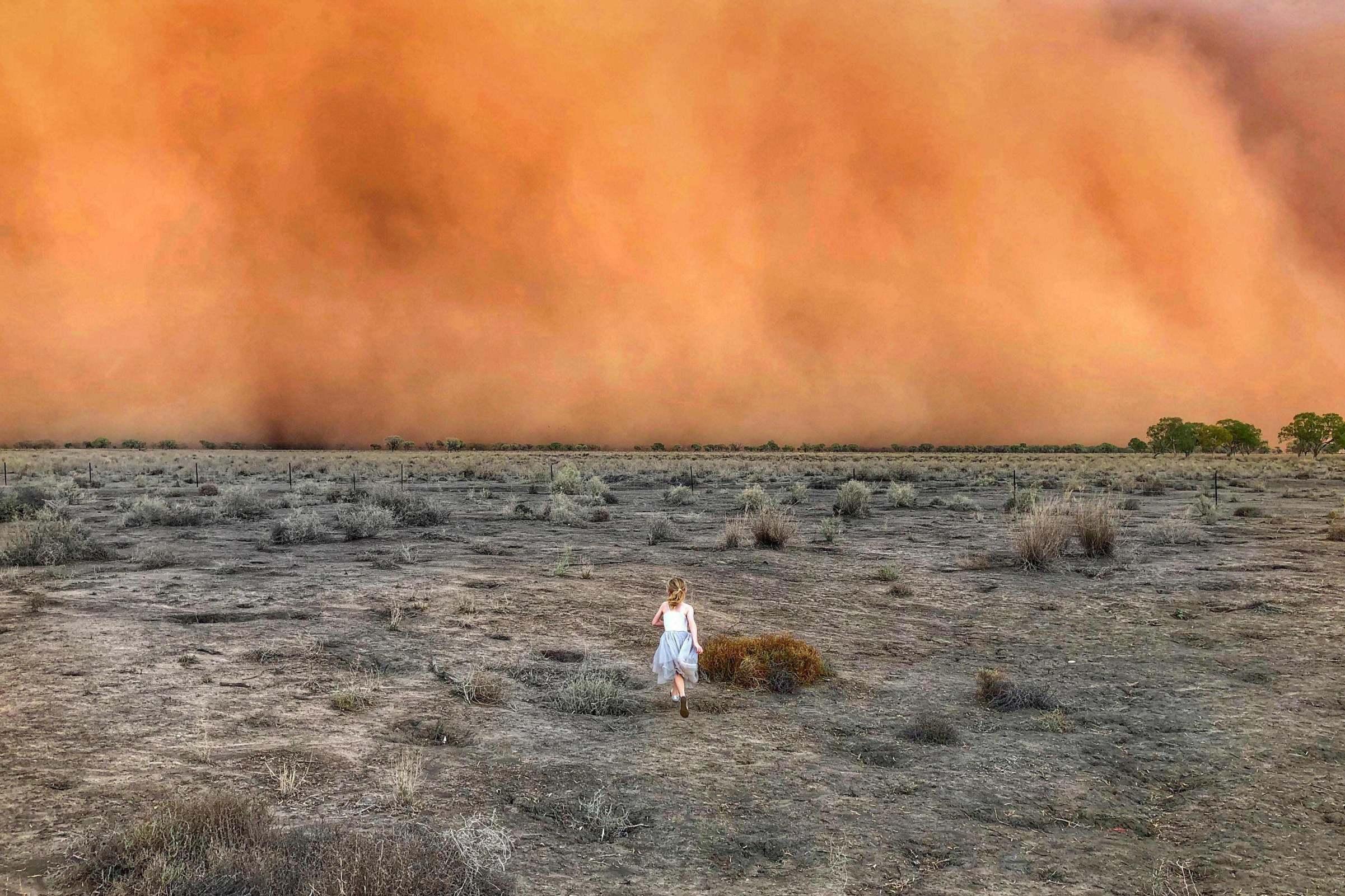 A girl running towards a dust storm, NSW, Australia by Uestrei Marcelino.