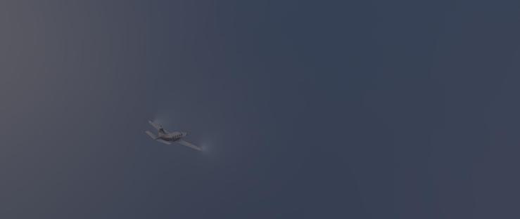 A small single-engine propeller airplane is flying through a dark sky with its landing lights illuminated, creating bright spots ahead of the aircraft. The plane is light-colored, possibly white or light gray, with darker accents along the fuselage and tail section. The background is a uniform deep blue-gray, indicating either nighttime or twilight with no visible clouds. The aircraft is positioned toward the left side of the frame, moving across the upper portion of the visible area. No other objects or features are present, emphasizing the solitary flight against the vast, dim sky. The overall scene conveys a sense of quiet movement through an empty, dark atmosphere.
