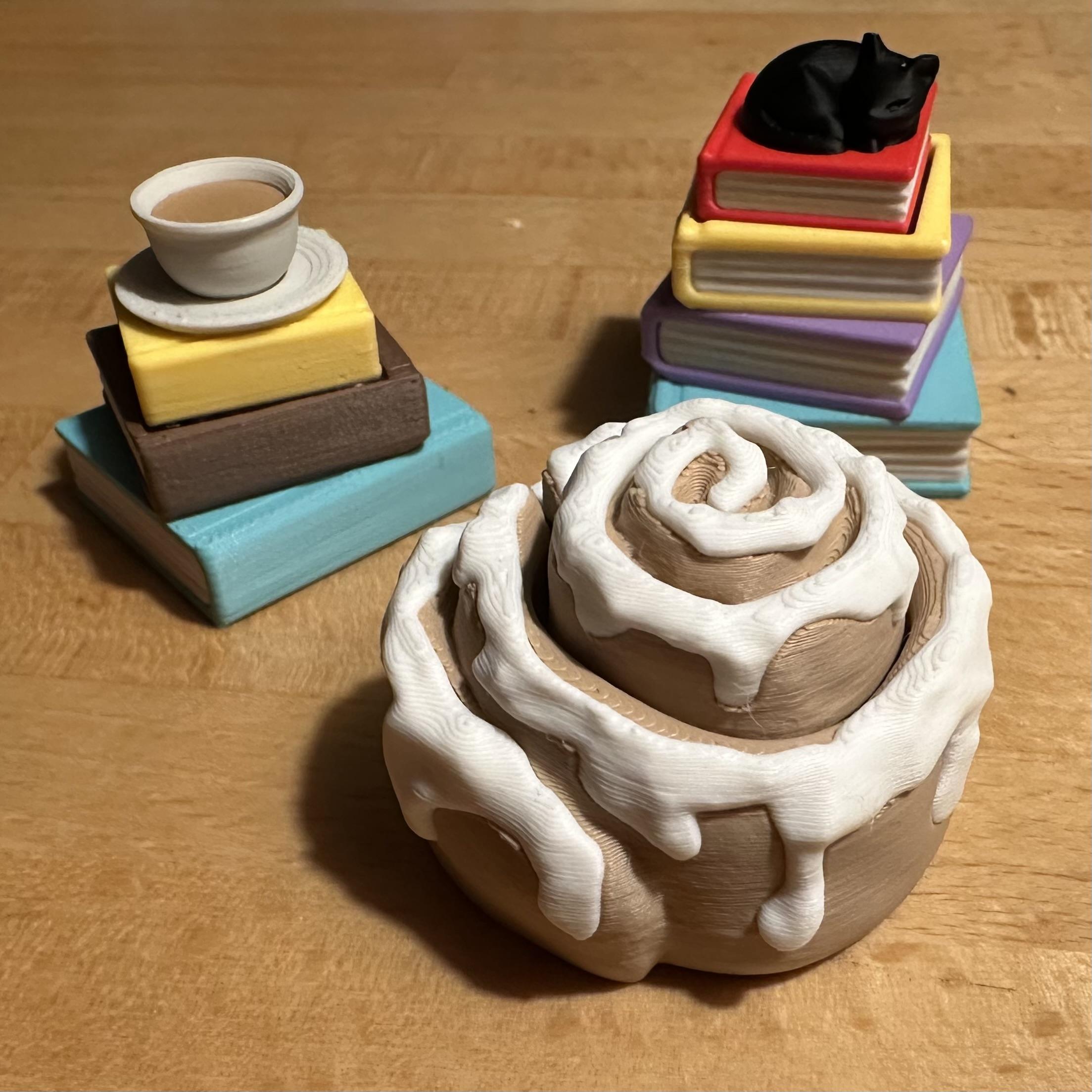 Utterly charming fidget toys: clicks cinnamon bun, a cat resting on a stack of books, and a cup of tea