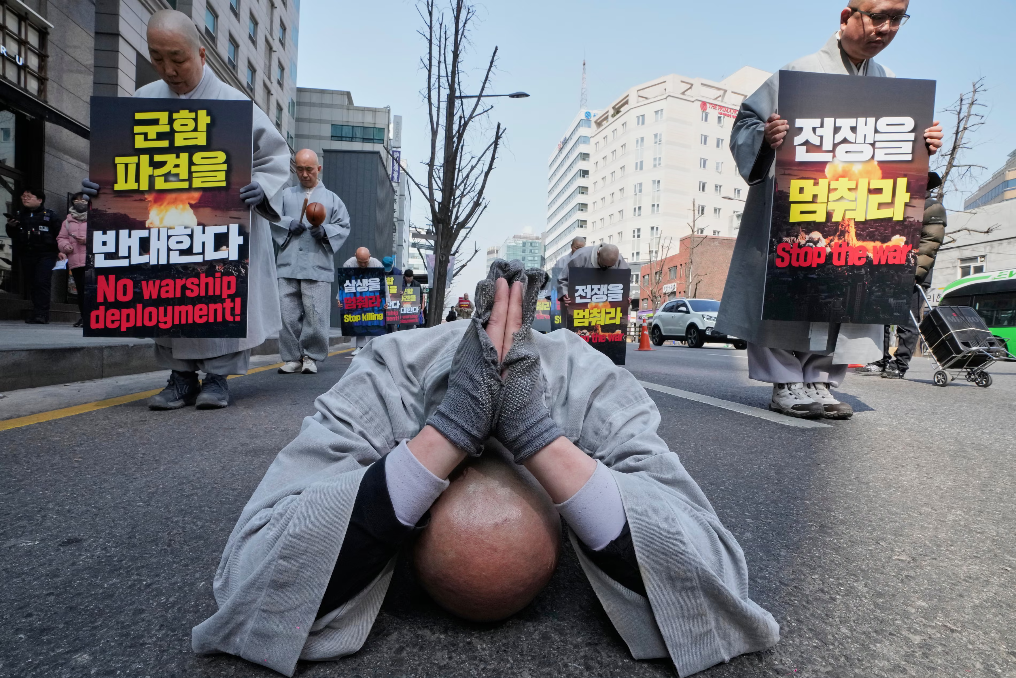 Buddhist monks march towards the US embassy, with one prostrating on the ground.
