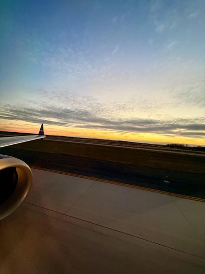 The sunset at Dulles airport with the wing of the plane and engine to the far left