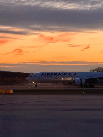 An AirFrance plane arrives on the runway with the sunsetting behind it
