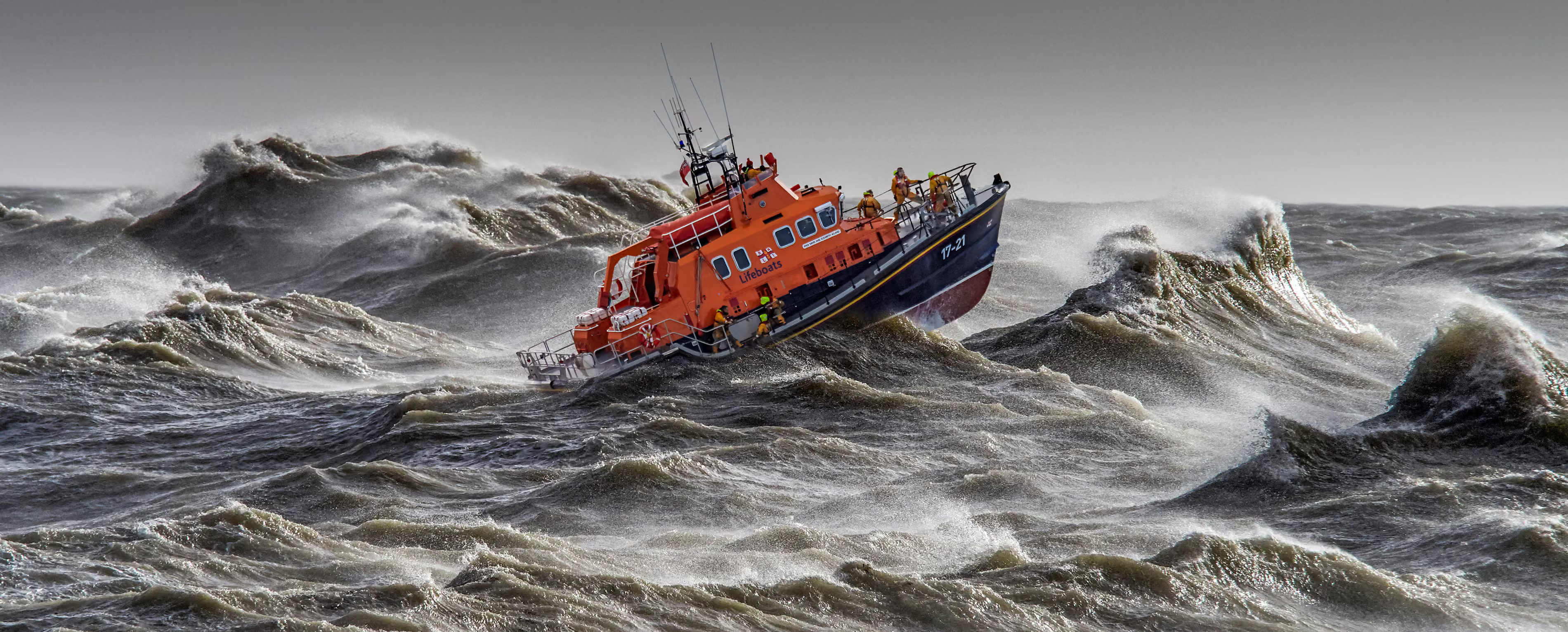A red lifeboat at a stormy grey sea.