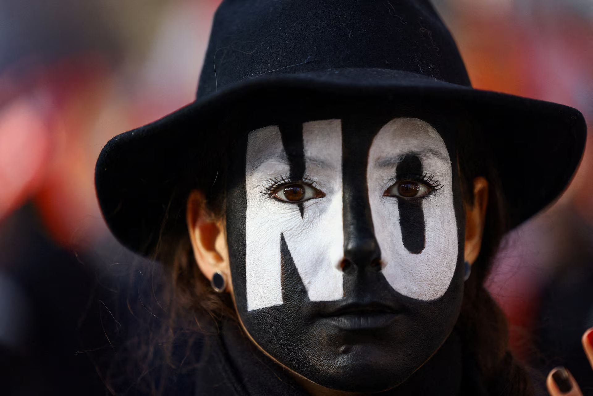 A demonstrator with the word "No" painted across their face.