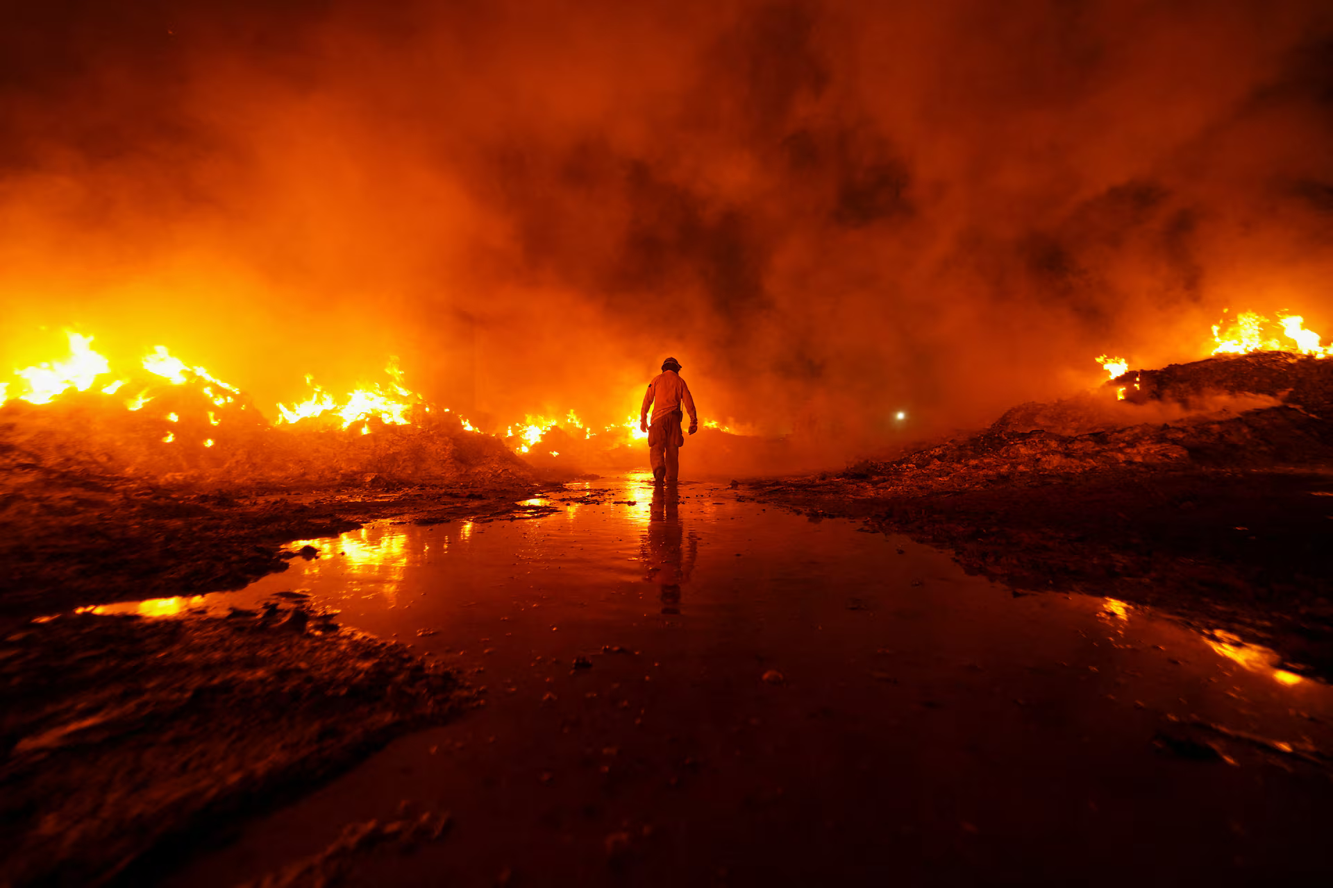 A firefighter walks amid flames.