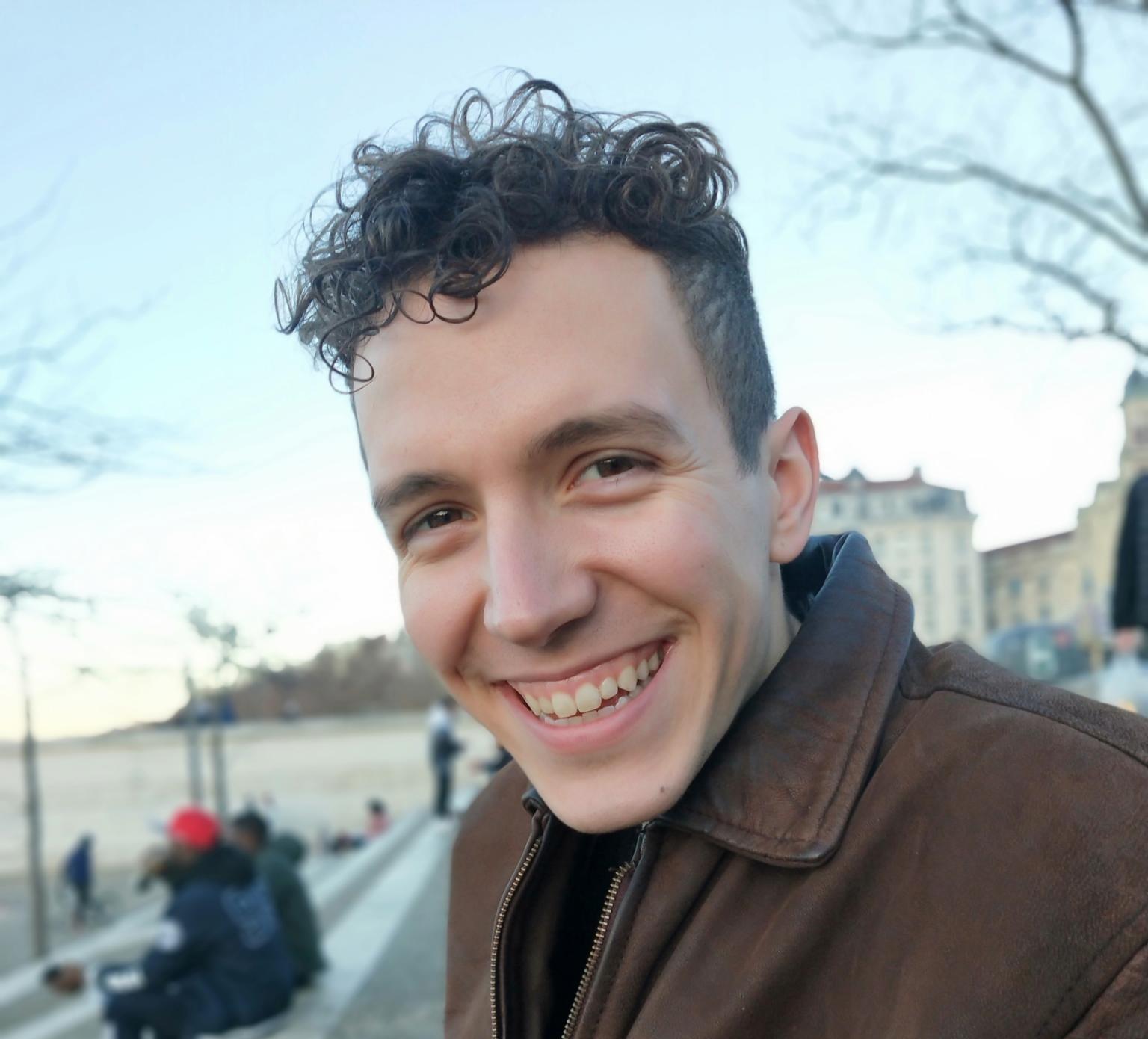 Kirk, a white man with short curly hair and a bright smile