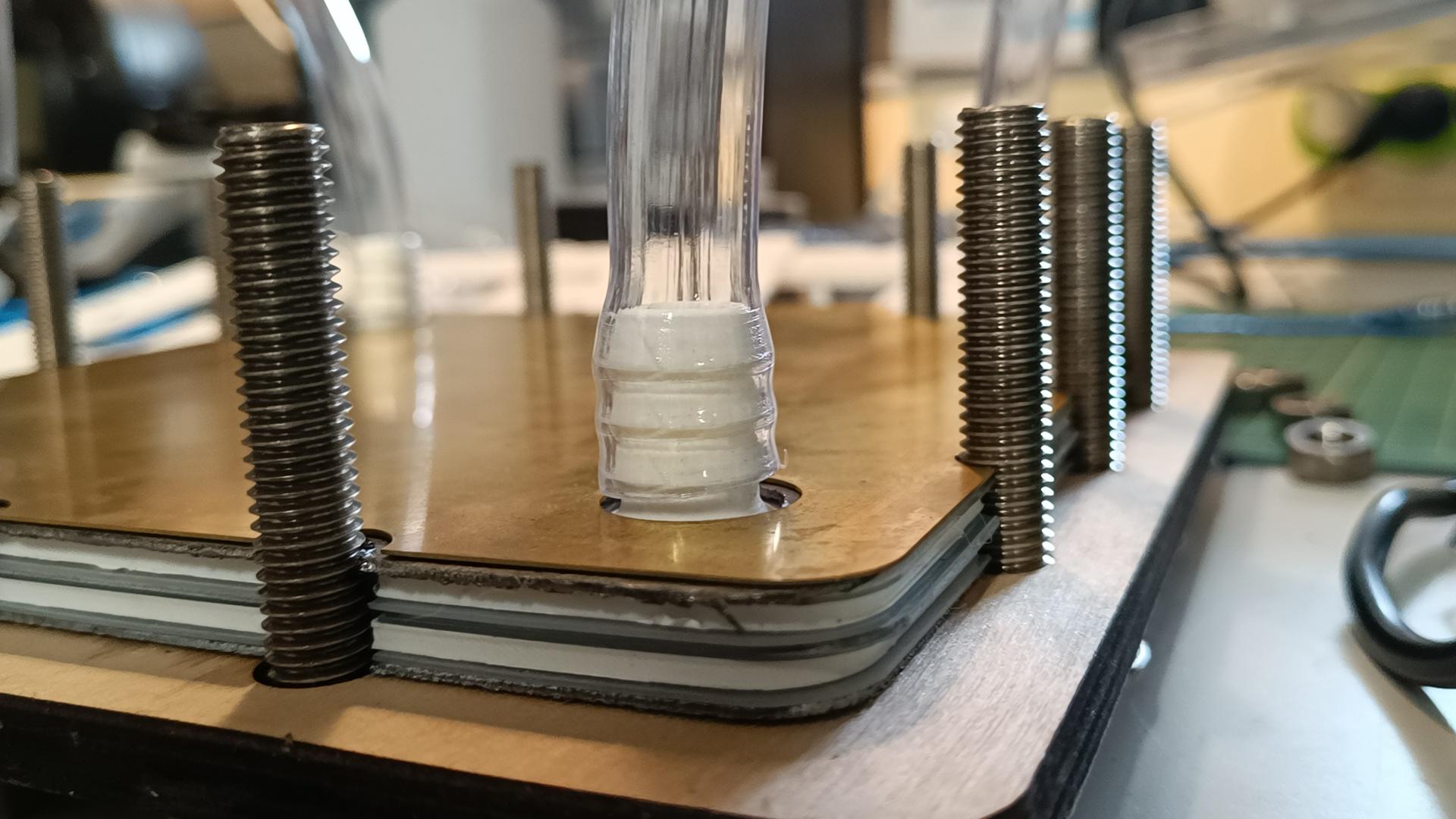 a flow battery, on a wood platform with scews and a tube coming out of it