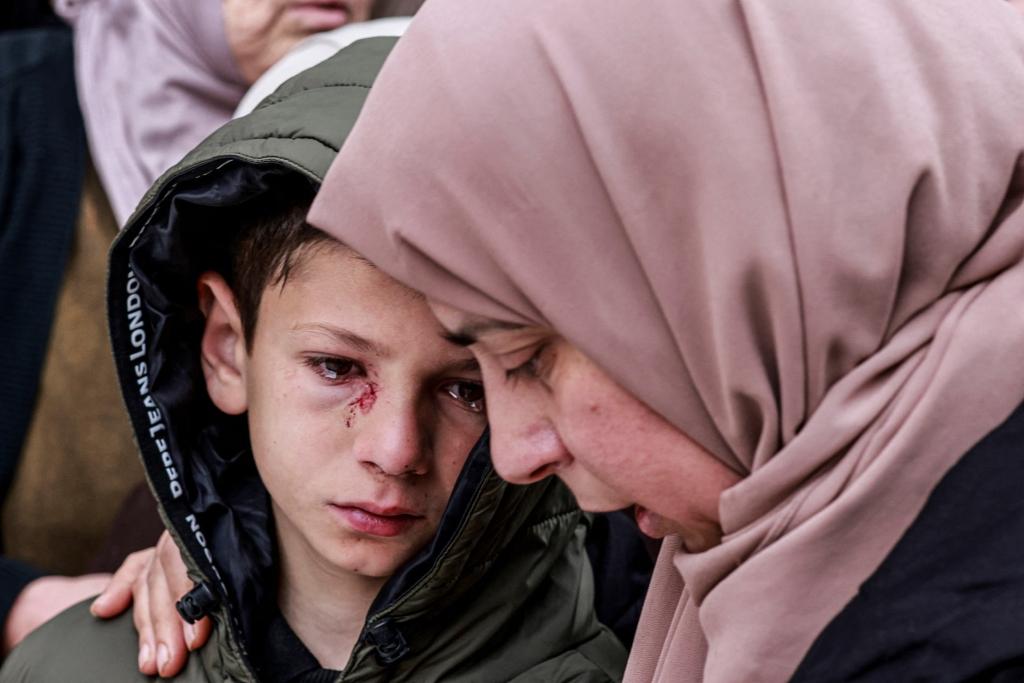 Mustafa, who was injured but survived after Israeli soldiers fired on the vehicle carrying his parents and two siblings, is comforted during the funeral of his family in the Israeli-occupied town.