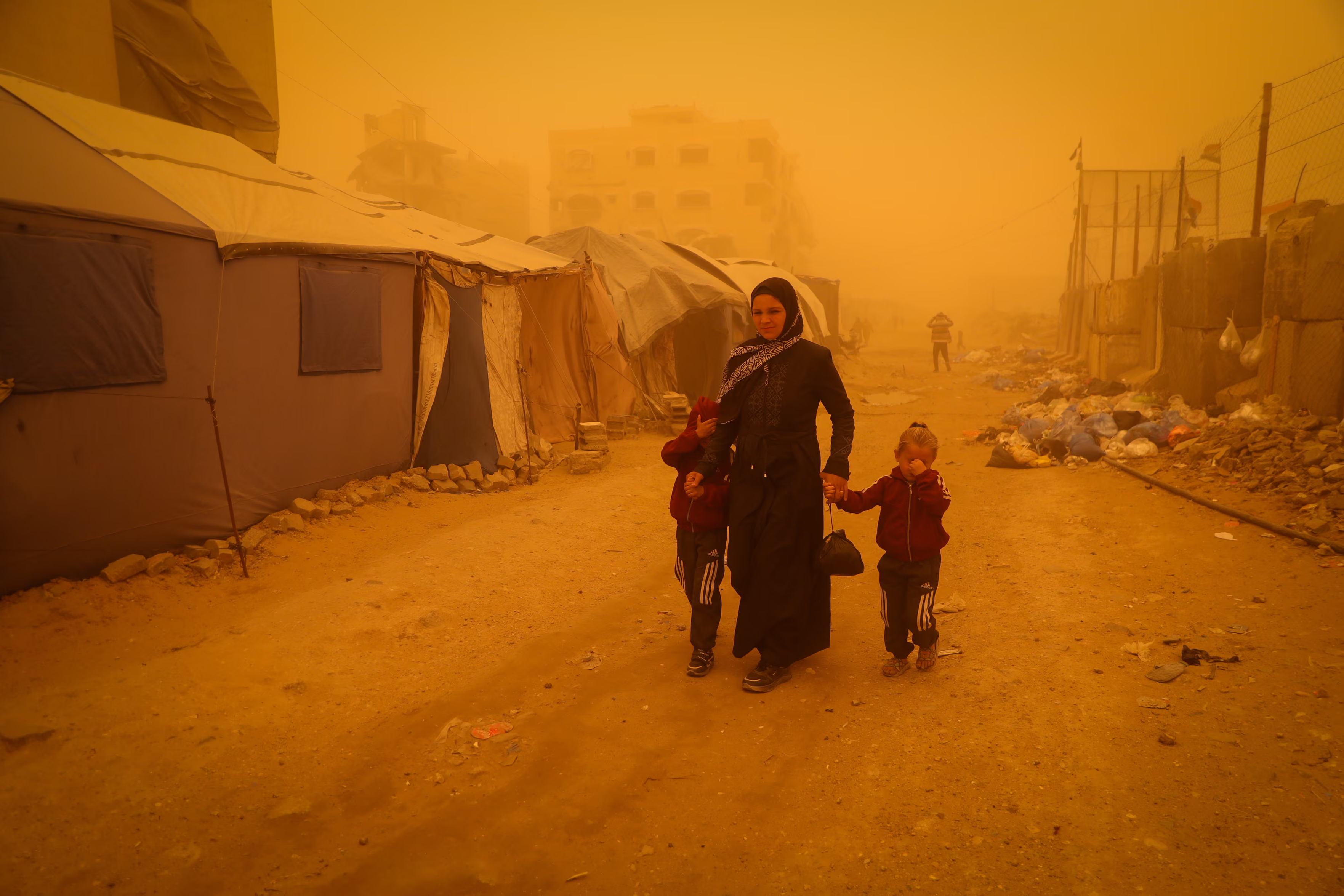 A woman with two young children walks in the dust storm.