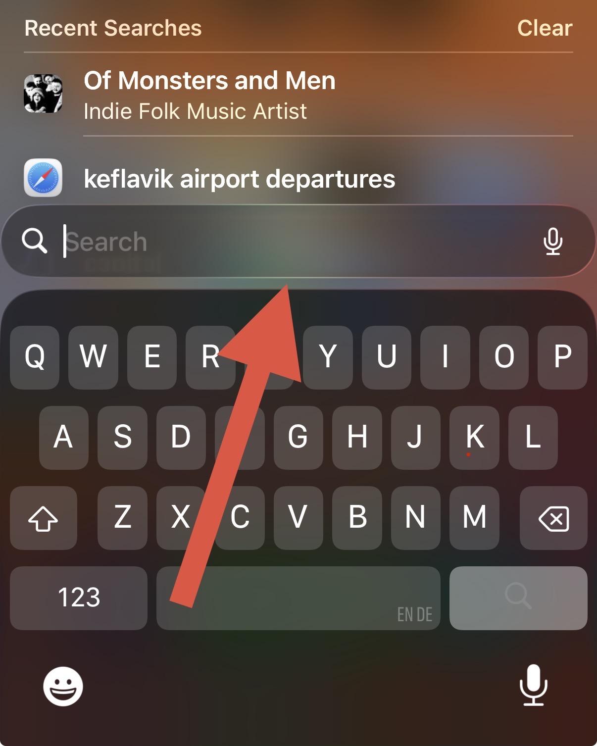 Screenshot of Spotlight search on iOS with a red arrow pointing to a highlighted area of the search bar