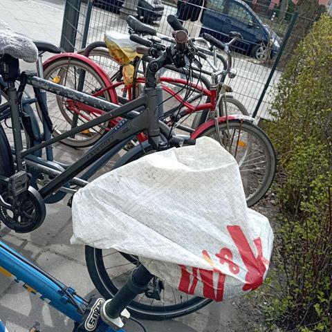 Ein Fahrradsattel mit H&M Einkaufsbeutel überzogen 
Im Hintergrund weitere Fahrräder, auch eins davon mit Tüte auf Sattel