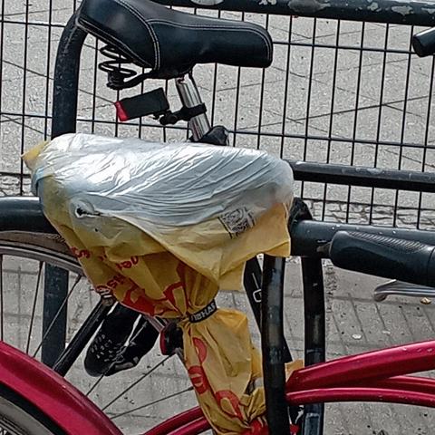 Ein Fahrradsattel mit undefinierbaren Einkaufsbeutel überzogen, sieht aus, als ob damit schon viele Jahre mit gefahren wid