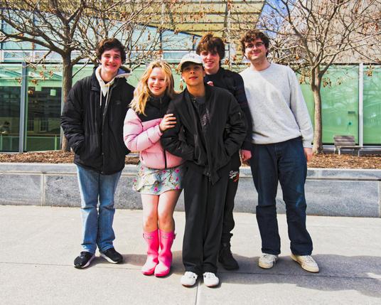 Five friends pose together and look excited in front of Cornell's Klarman Hall
