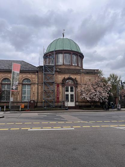Gebäude der Orangerie mit Kuppel und Magnolienbaum.