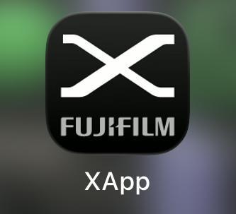 A screenshot showing the Fujifilm X app icon, a wide, angular X in white against a gradiated dark gray and black background, with the word “Fujifilm” in all caps and dark gray underneath it. The app’s name is “XApp”.