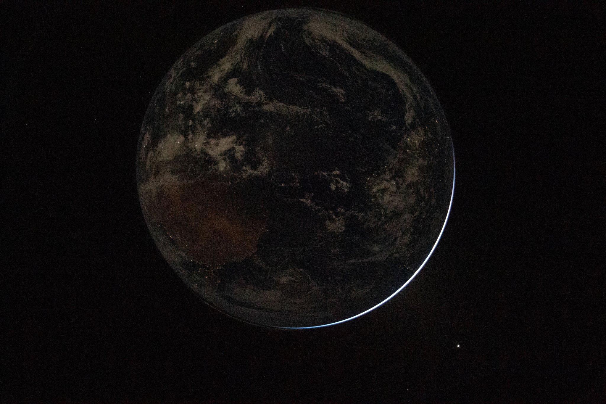 In this image of Earth taken by the Artemis II crew, we can see the electric lights of human activity. In the lower right, sunlight illuminates the limb of the planet.