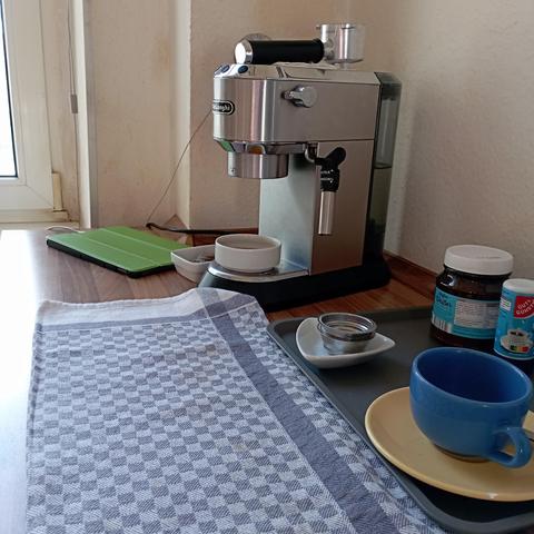 A blue white squared "Grubentuch" kitchen towel,
Some other items for making a coffee,
A De'Longhi #dedica portafilter machine 