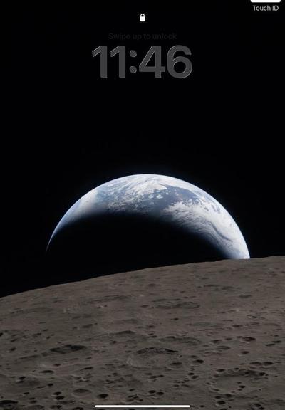 A screenshot of an iPad lock screen with the NASA photo showing the moon in the front and the Earth in the background. The time of 11:46 appears in the top middle, and the text “Touch ID” is in the upper right corner.