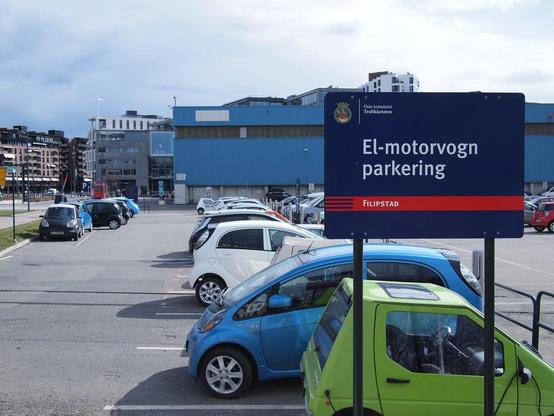 Cars in a car park. Large sign with text in Norwegian: El-motorvogn parkering Filipstad [Electric vehicle parking, Filipstad]