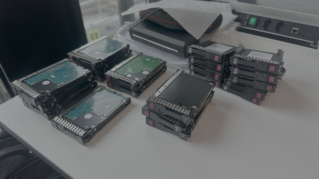 Mehrere Stapel von 2.5 - Zoll Harddisks und SSD liegen auf einem Schreibtisch