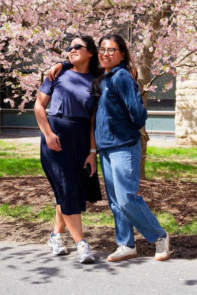Two woman pose in front of flowering tree