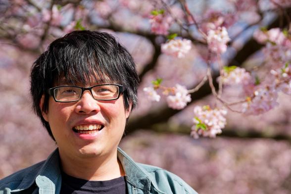 Man with glasses in front of Sakura between Olin Library and Sage Chapel