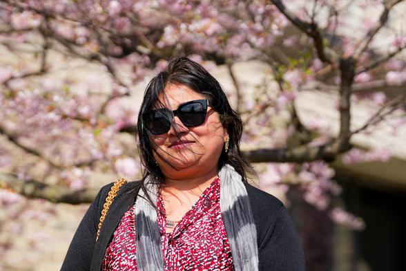 Woman poses in front of Olin Library cherry trees