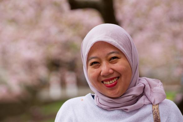Smiling woman with headscarf with pink blossoms filling the space behind