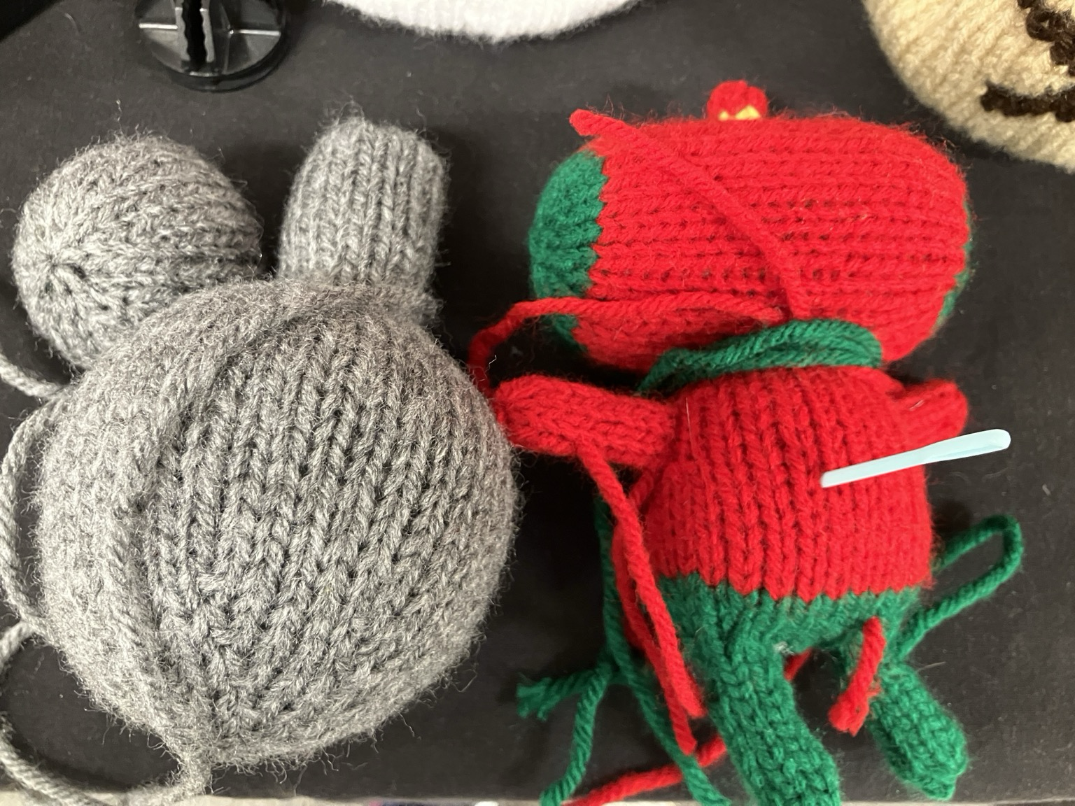 Some knit plush pieces. 2 are gray blobs and one is red and green