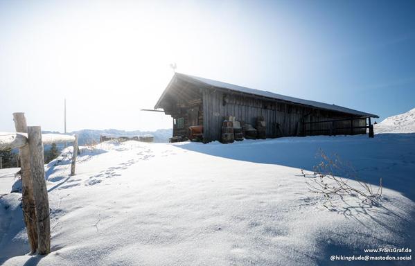 A snow field with a hut in the midground.
