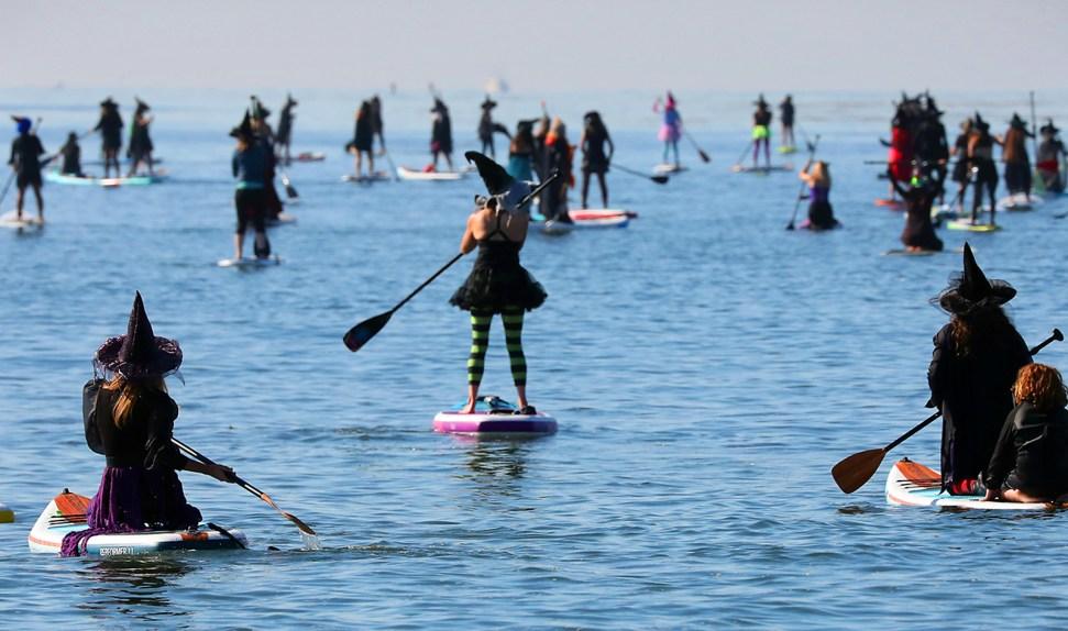 dozens of witches on stand-up paddle boards