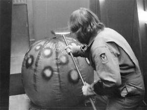 Scene from the film Dark Star. A man is fighting off a giant beachball like alien with a broom