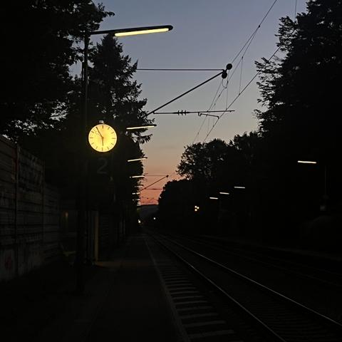 Uhr an einem Bahnsteig, 5:55, Sonnenaufgang 