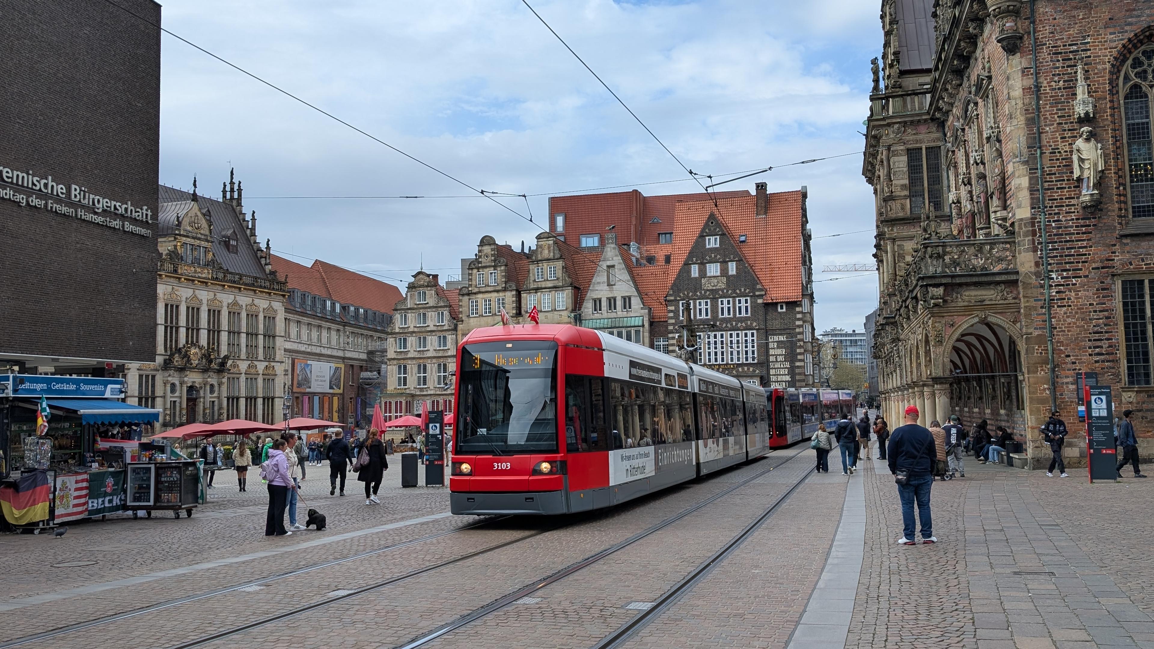 A BSAG GT8N-1 tram with commercial livery crossing Bremen Marktplatz with its historical buildings