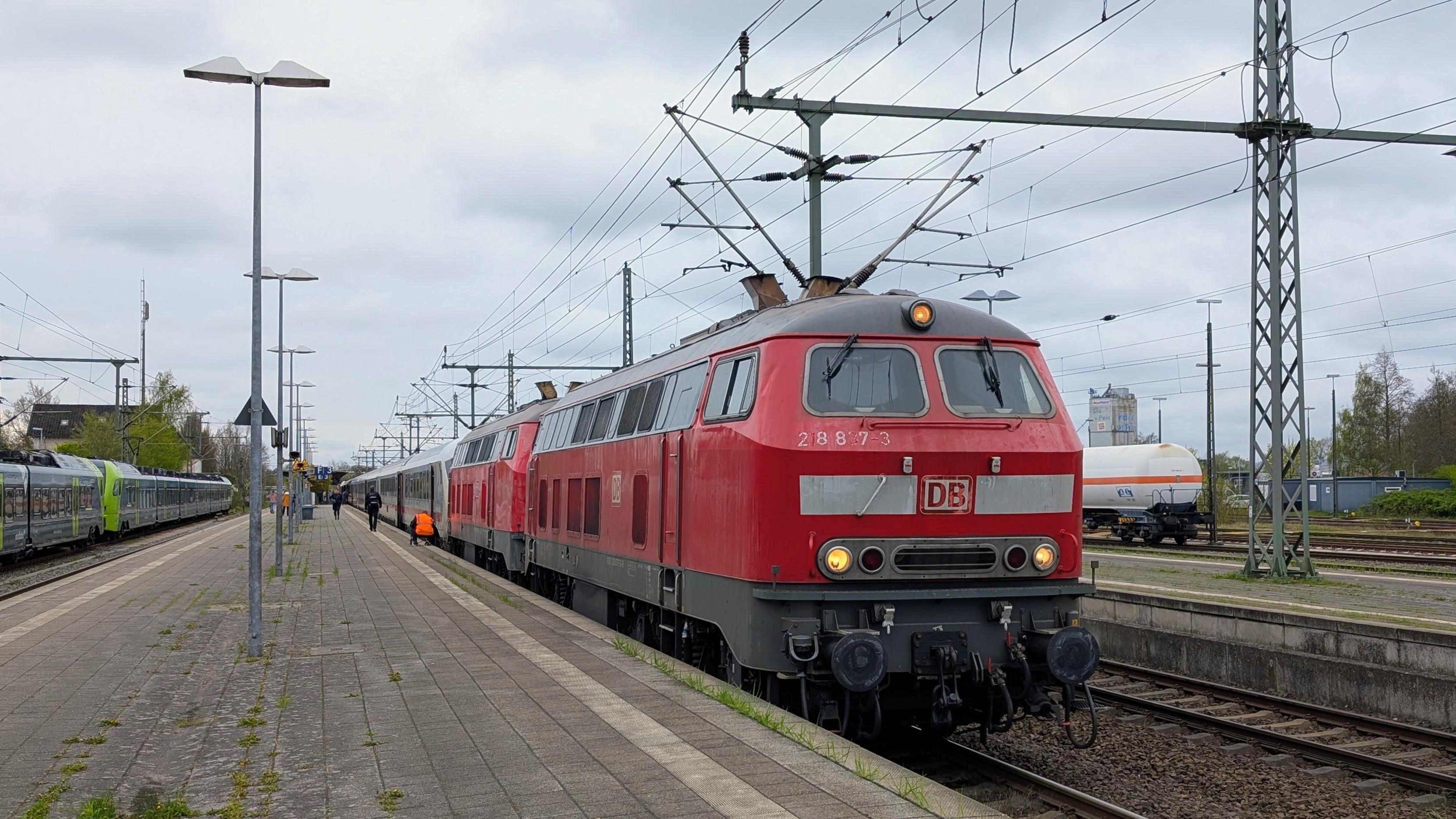 Two DB Class 218 locomotives coupled to an IC 1 train at platform in Itzehoe, roofing at the end of the platform, two Nordbahn Flirts on a track in the background