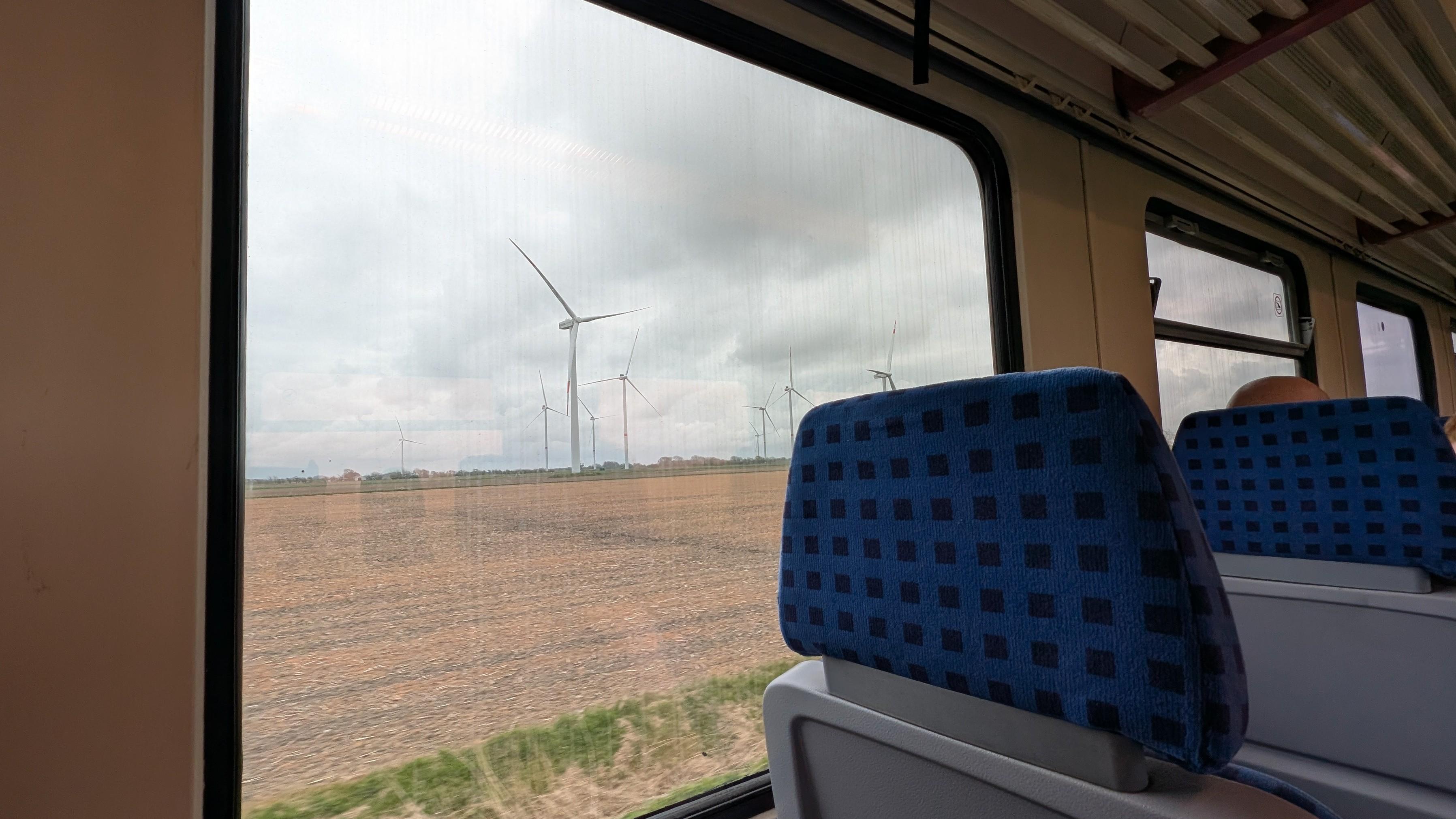 Interior of the train, 2+2 seating configuration, blue seat pads, fields and wind turbines
