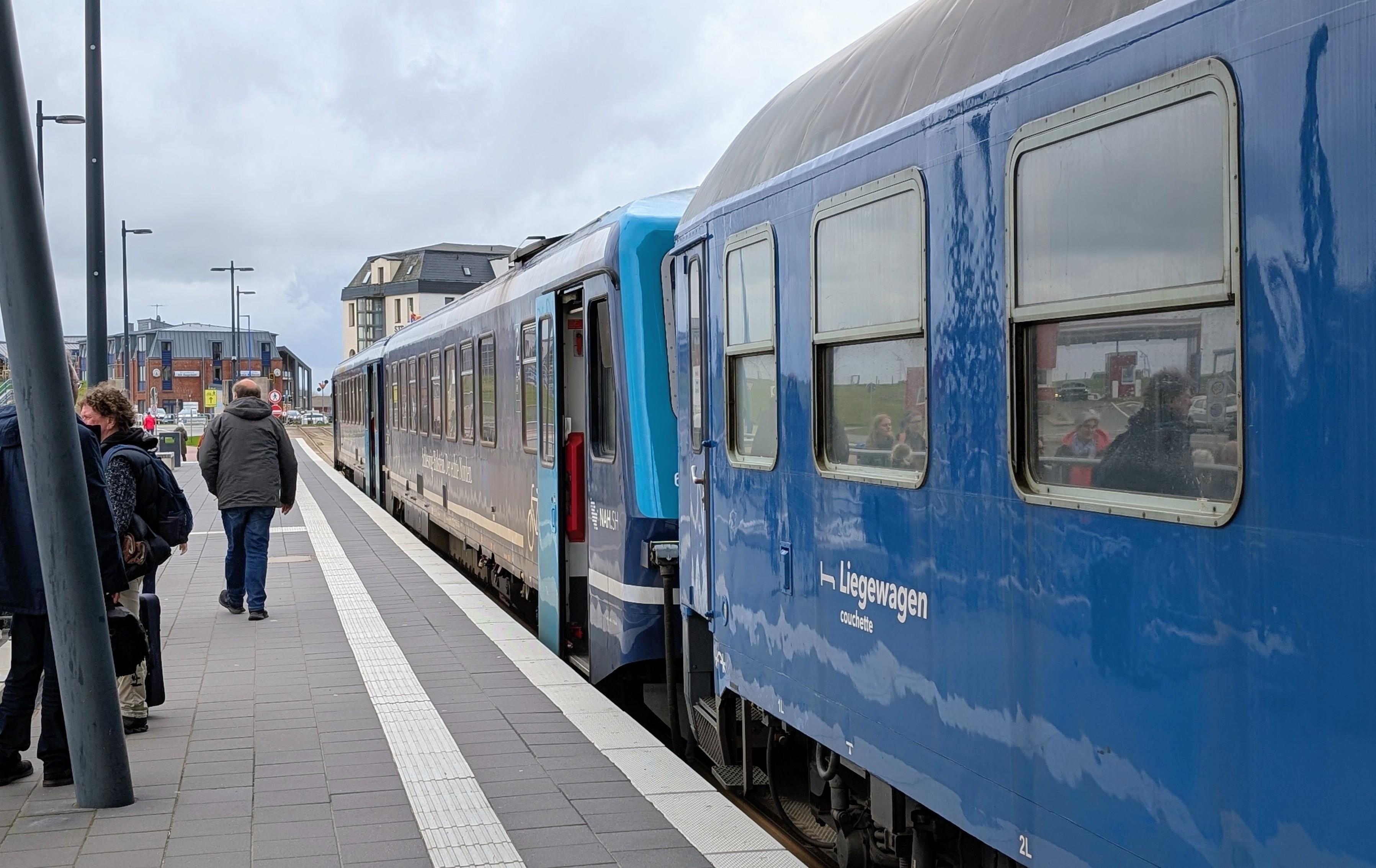 A blue RDC sleeper coach coupled at a RDC Class 628 DMU at the platform in Dagebüll Mole, passengers leaving the platform