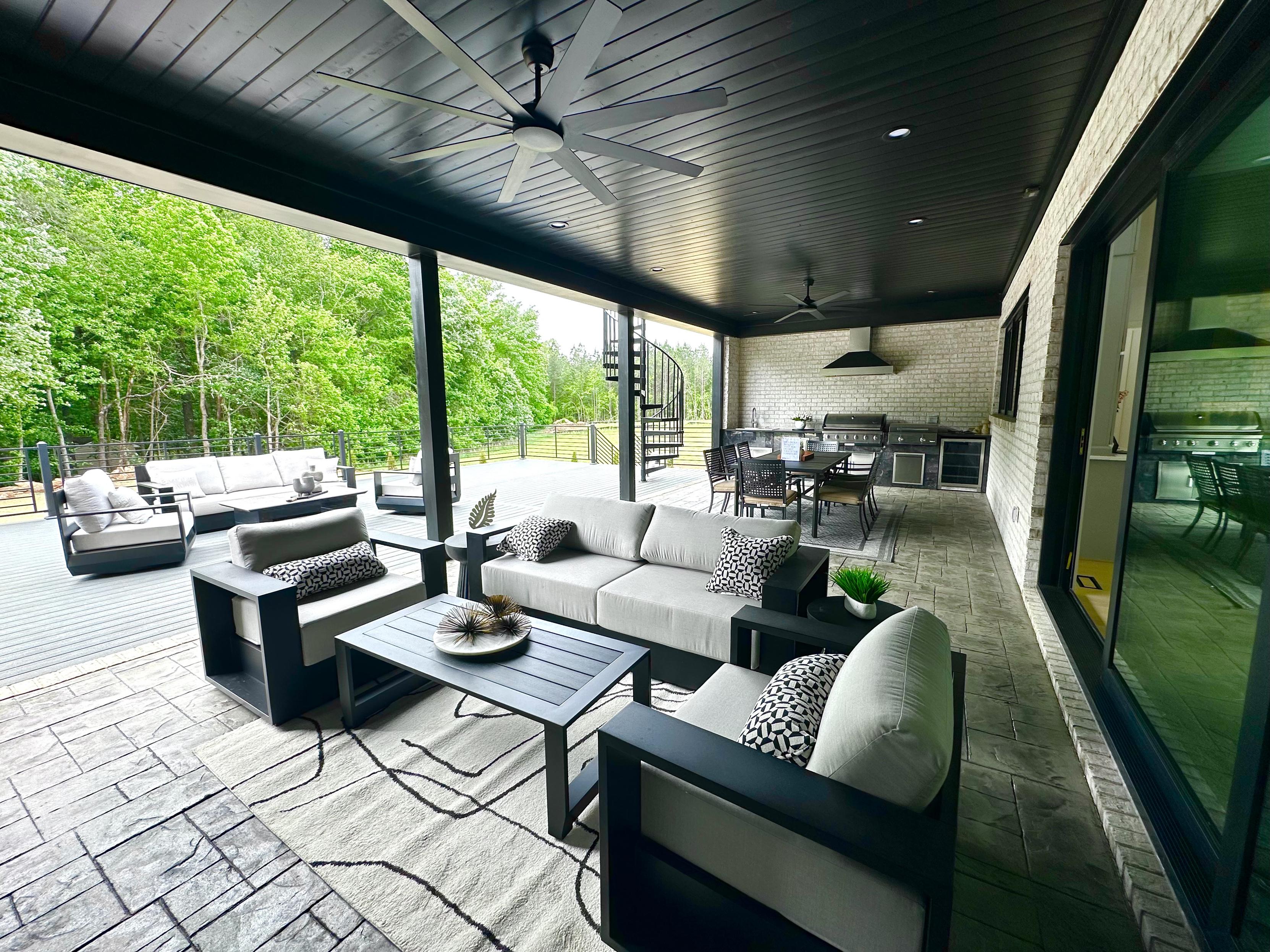 A huge outdoor patio half covered with a giant outdoor grill.