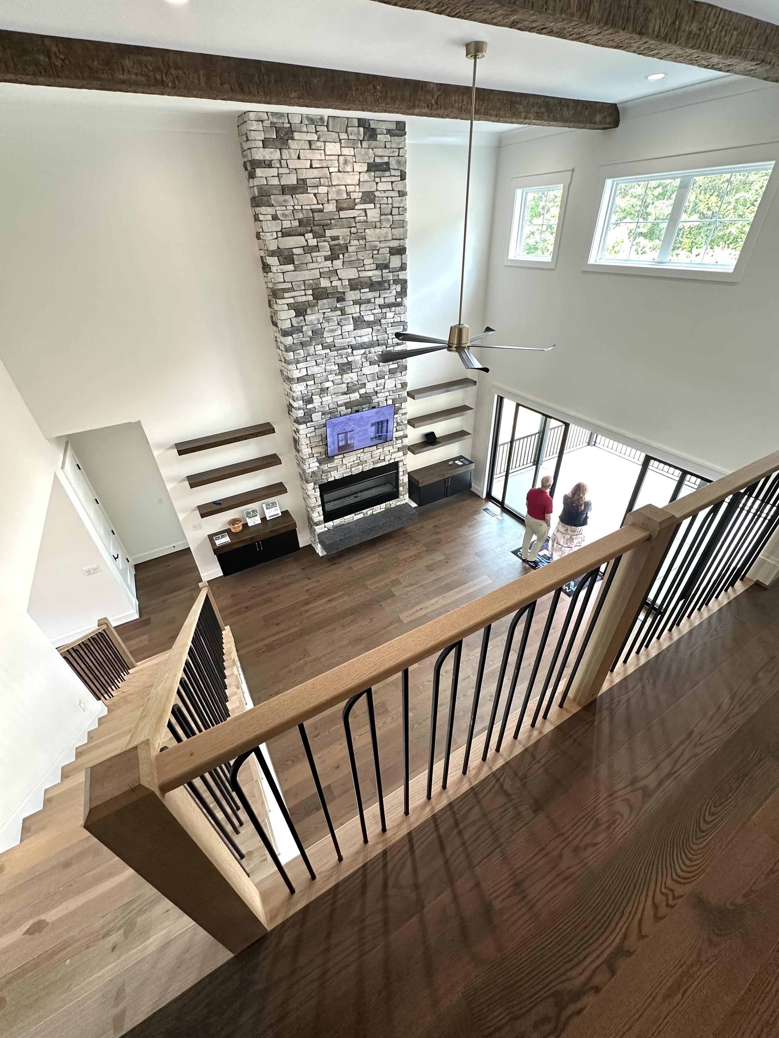 Looking down into the great room from the second floor. A beautiful grey stone chimney climbs all the way to the ceiling.