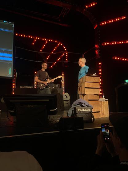 Bastian playing the guitar on stage while André tunes in the neural-amp-modeled distortion 