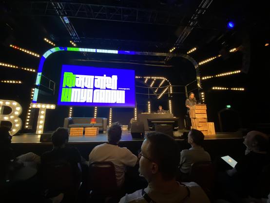 Kimya Gandhi on stage at beyond tellerrand with the title screen of her talk The Act of Pressing a Key: The Journey of a Letterform on to Your Screen