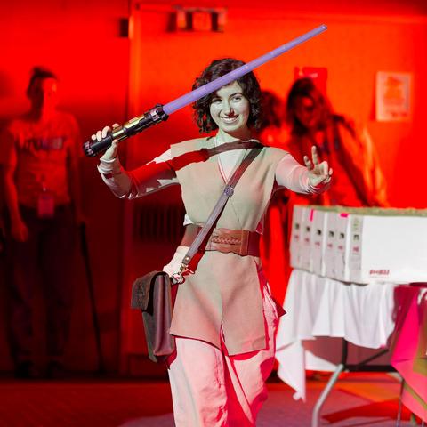Princess lea with a large bag and light purple lightsaber with lighting that looks strangely red in bac