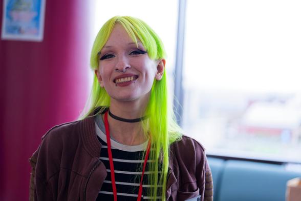 Girl with a gradiant of green hair lit up from behind with soft light