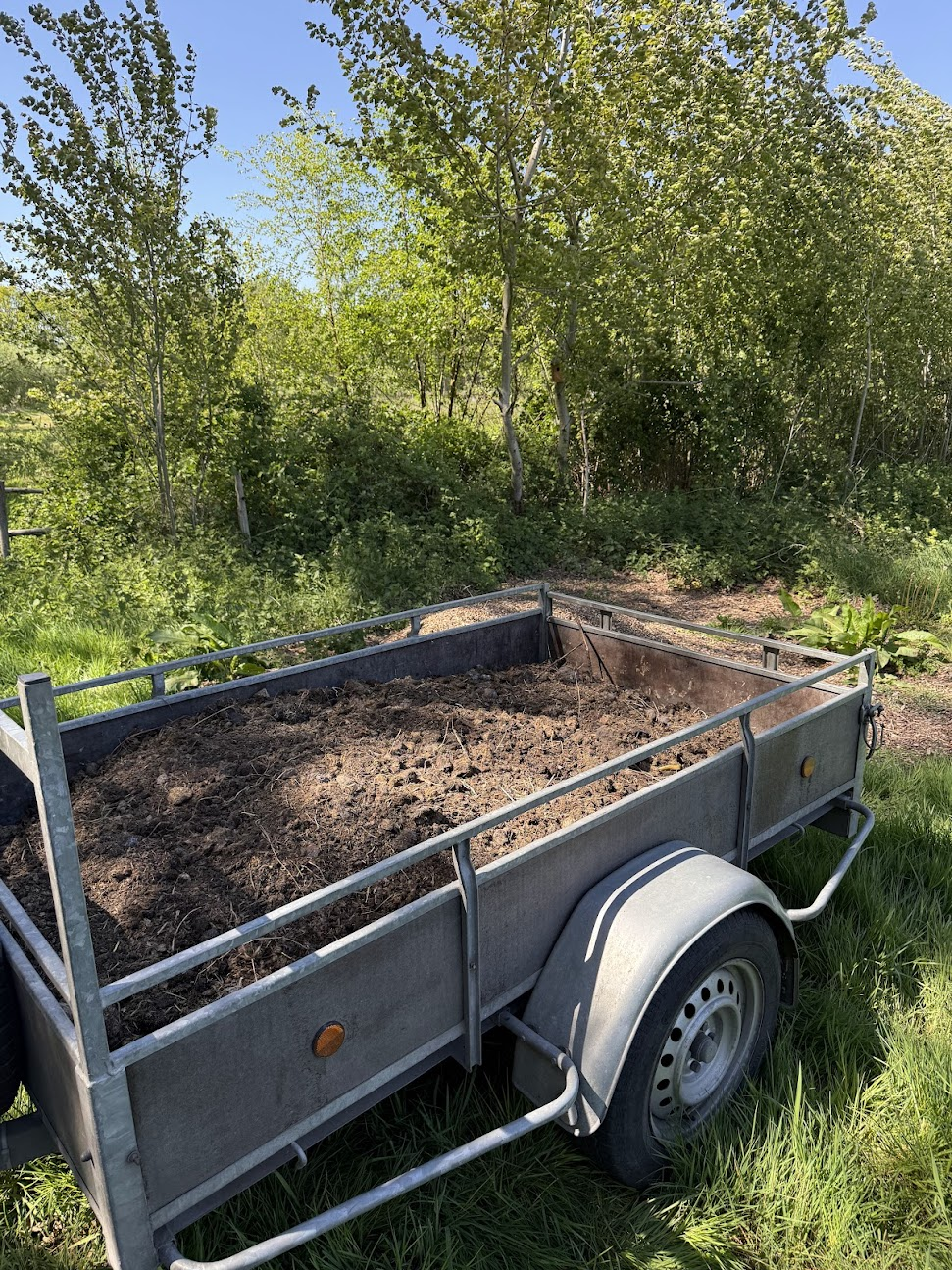 Trailer with aged horse manure in a green setting