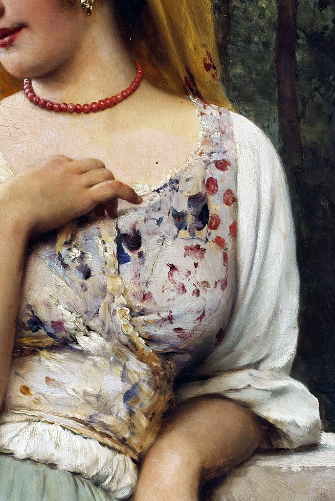 A close-up detail of a classical painting showing the torso of a woman. She wears a white blouse under a patterned corset with red and blue floral motifs and a red beaded necklace. Her hand is resting near her chest, and a yellow veil is visible behind her head.